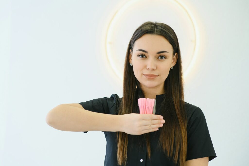 A beautiful woman, an employee of a beauty studio, holds eyebrow brushes in her hands.